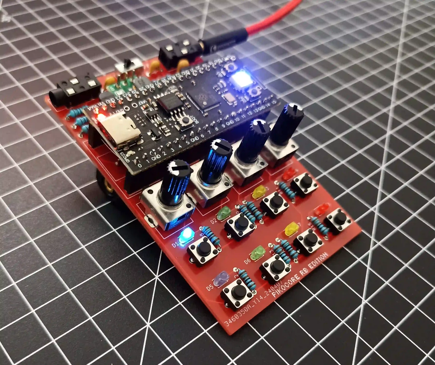 ivndbt's completed red Pikocore re-edition circuit board illuminated on a gridded work surface