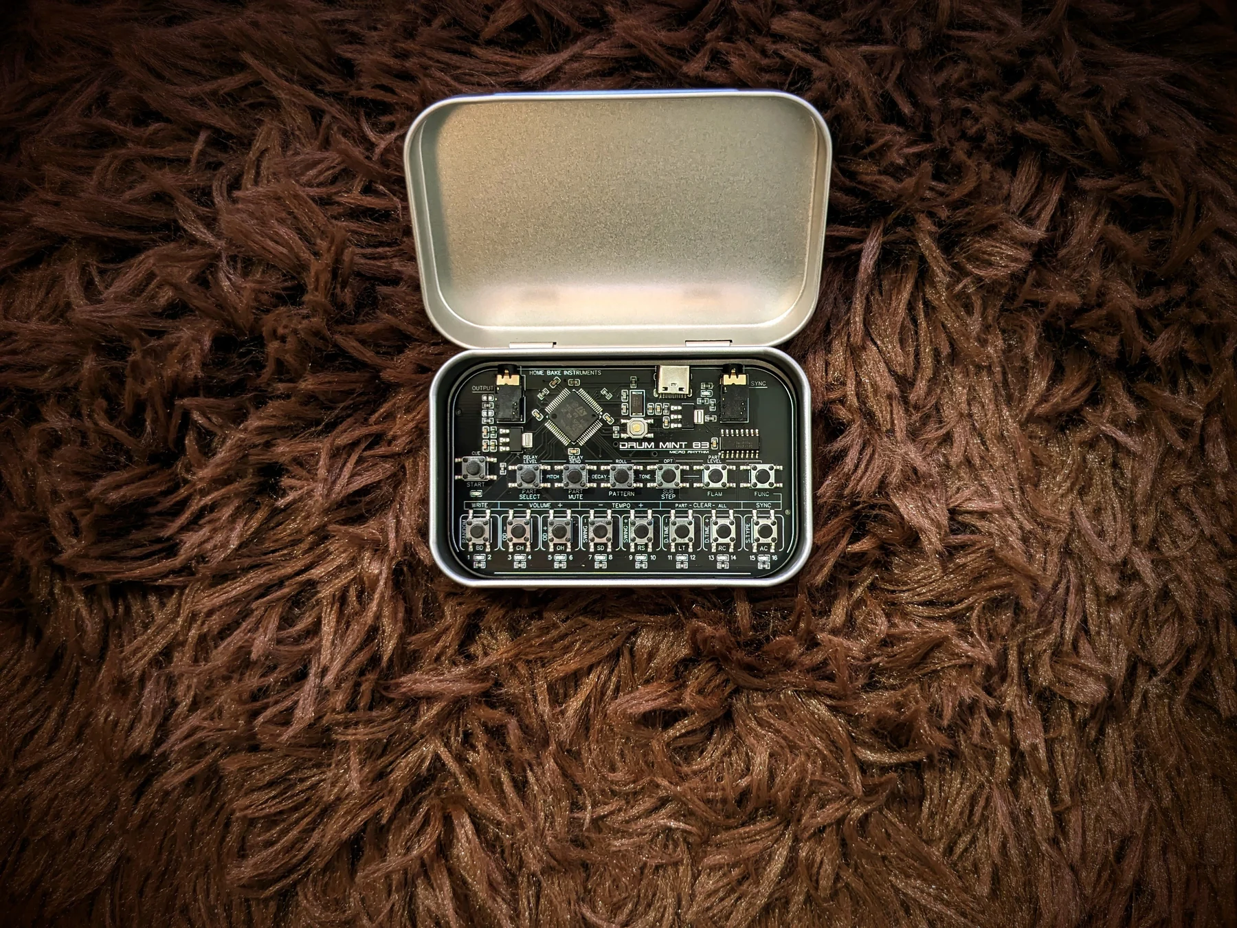 A HOME BAKE INSTRUMENTS DRUM MINT 83 rhythm machine resting inside an open mint tin