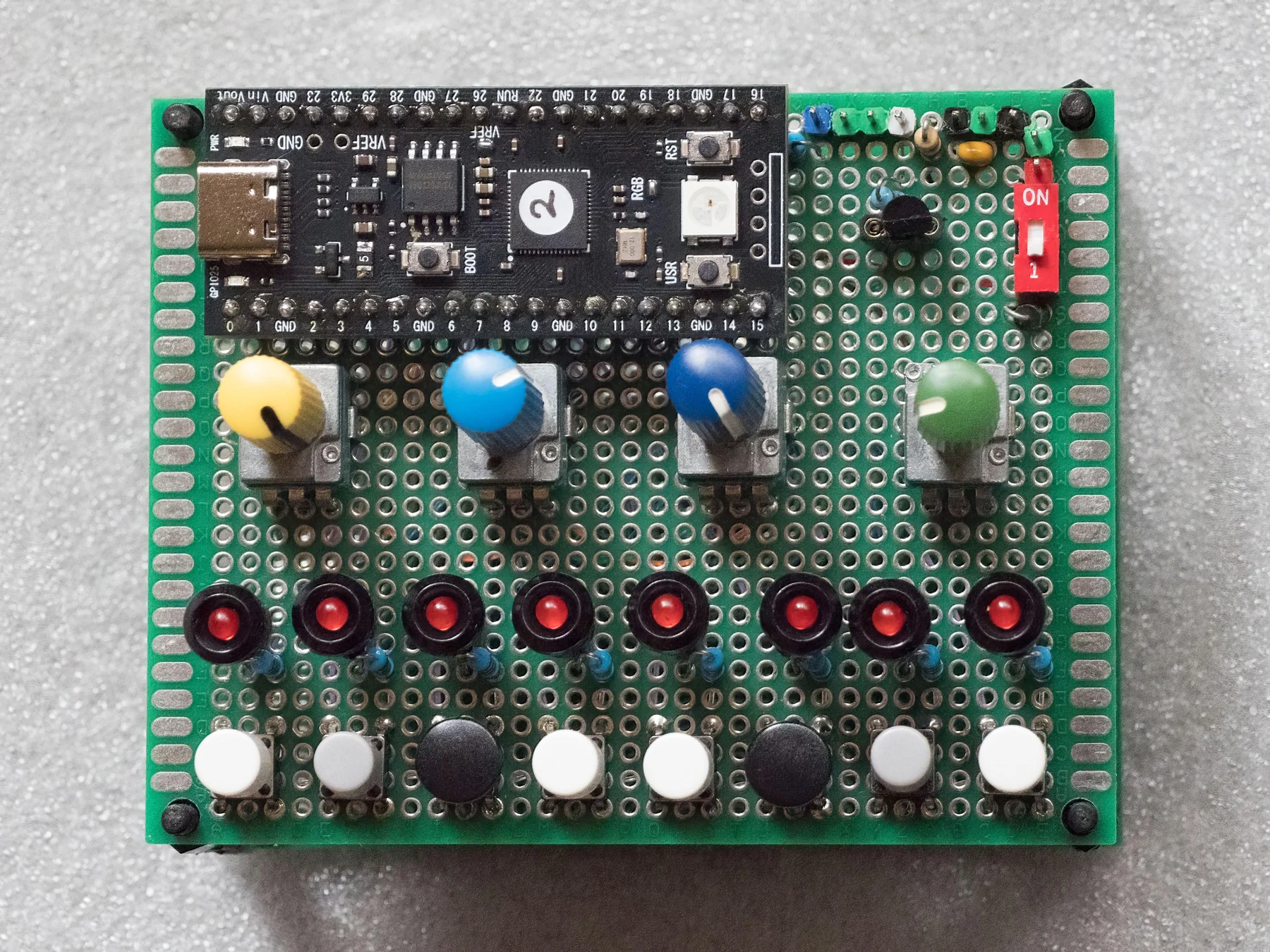 Bellabebop's hand-built 7 by 9 Pikocore on green perfboard with four colorful knobs and two rows of buttons