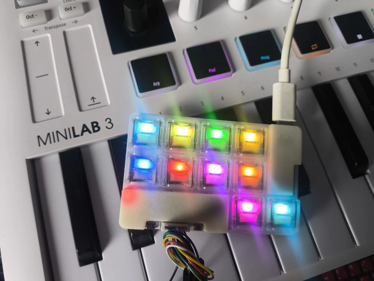A ten-key PNCATEHO low-profile keyboard glowing in multiple colors while running the Nizkore Pikocore port