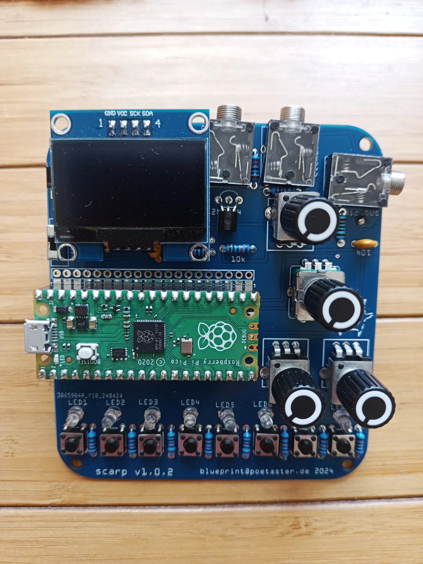 The open-hardware Scarp RP2040 music platform assembled with two rows of buttons, LEDs, knobs, and a central encoder