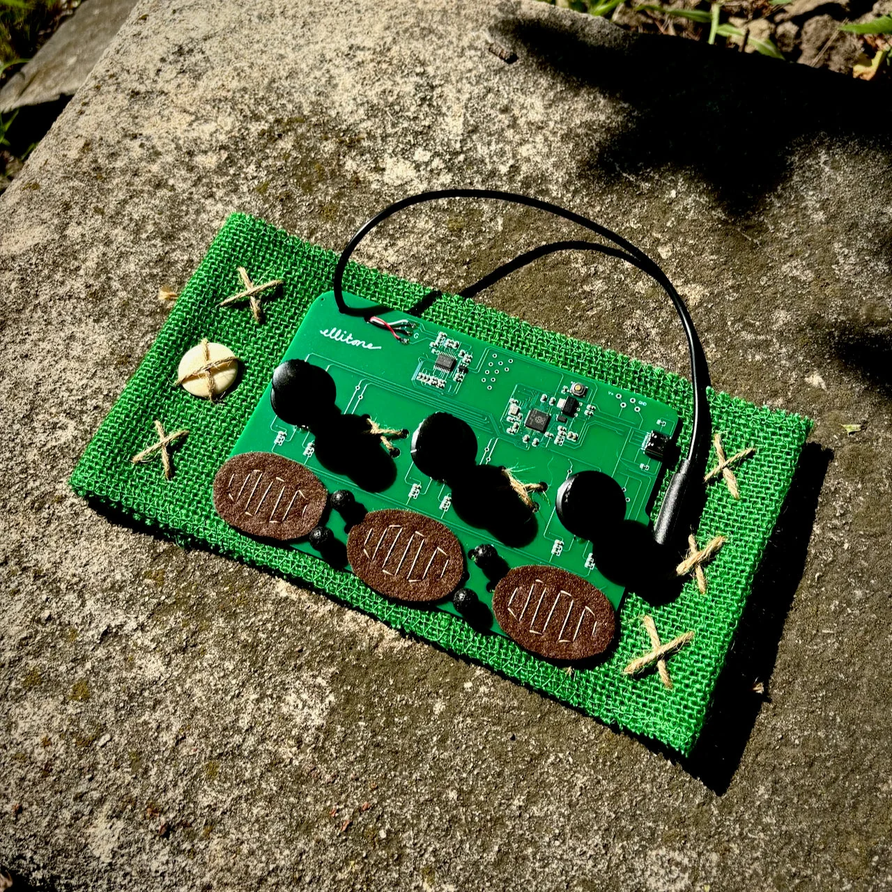 An Ellitone groov-e generative synthesizer in a green handmade textile enclosure outdoors